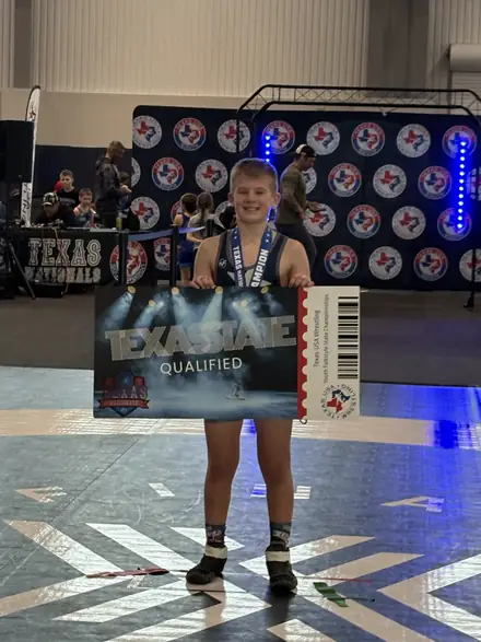 An AWC wrestler at the state qualifier backdrop after punching a ticket