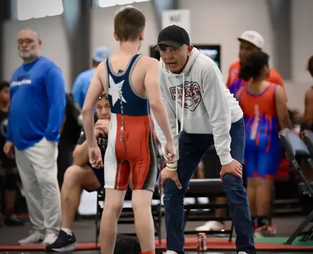 A coach talking a wrestler through his match plan between periods