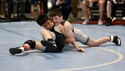 Two young wrestlers battle on the blue tournament mat