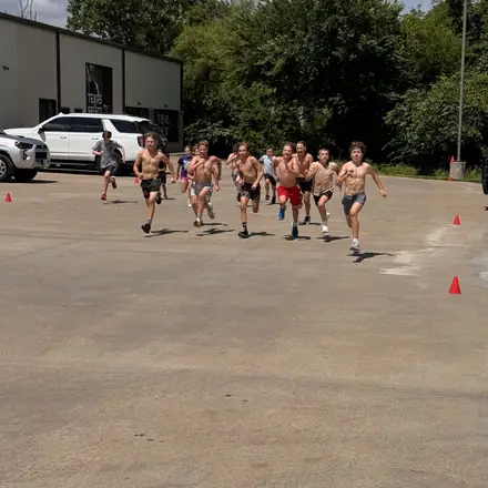 Wrestlers spread across the blue mat at the start of a drilling session.