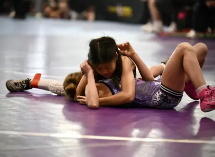 Two girls compete on the mat at a youth wrestling tournament