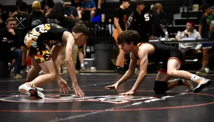 Two wrestlers explode out of their stances at the whistle