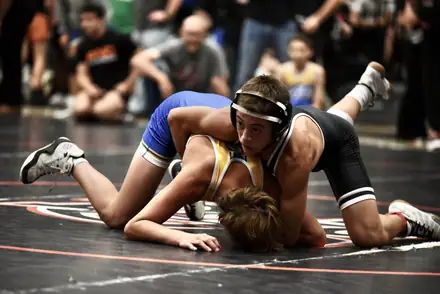 An AWC wrestler controls an opponent on the mat at a state tournament