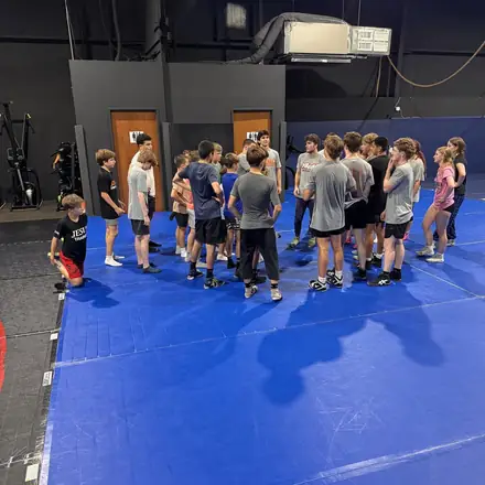 Partners squaring up in neutral position under the gym's championship flags.