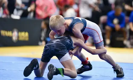 A young wrestler finishes a takedown at a state tournament