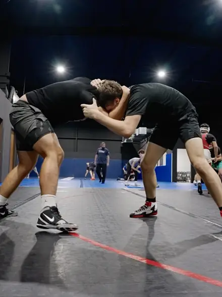 Two high school wrestlers tied up in a collar tie during live wrestling.