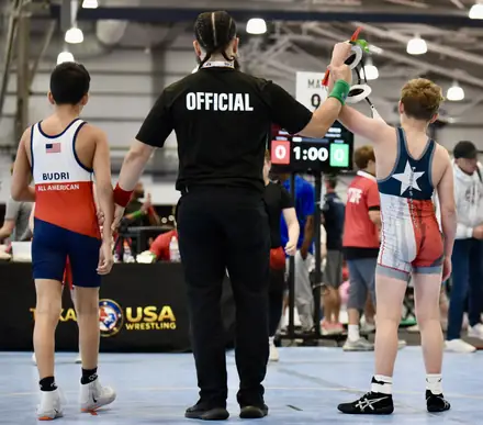 An official sets two wrestlers before the start of a tournament match