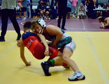 A wrestler defends a shot during a match at a state tournament