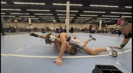 Two wrestlers battle on the blue competition mat during a match
