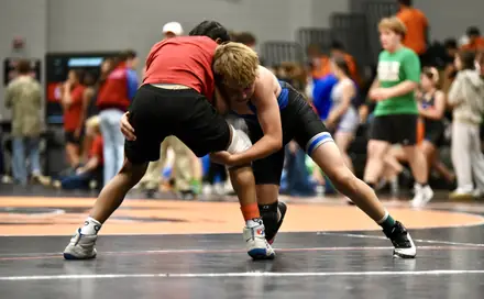Two wrestlers battle for position during a hard-fought bout in the gym