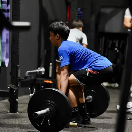 An AWC athlete pulling a barbell from the floor during strength and conditioning.