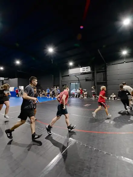 A line of wrestlers running the perimeter of the training floor.