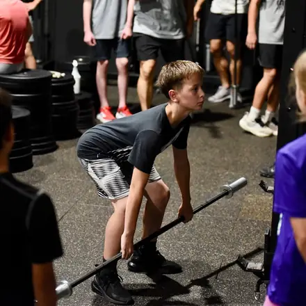 A young athlete setting up over a barbell in the strength and conditioning session.