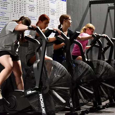 AWC athletes working a row of air bikes during conditioning.
