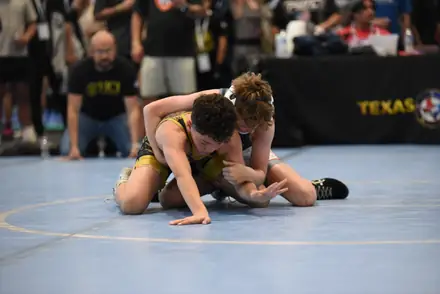 An AWC wrestler turns an opponent on the blue mat at a Texas USA Wrestling event