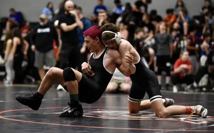A wrestler shoots a low single leg during a tournament bout