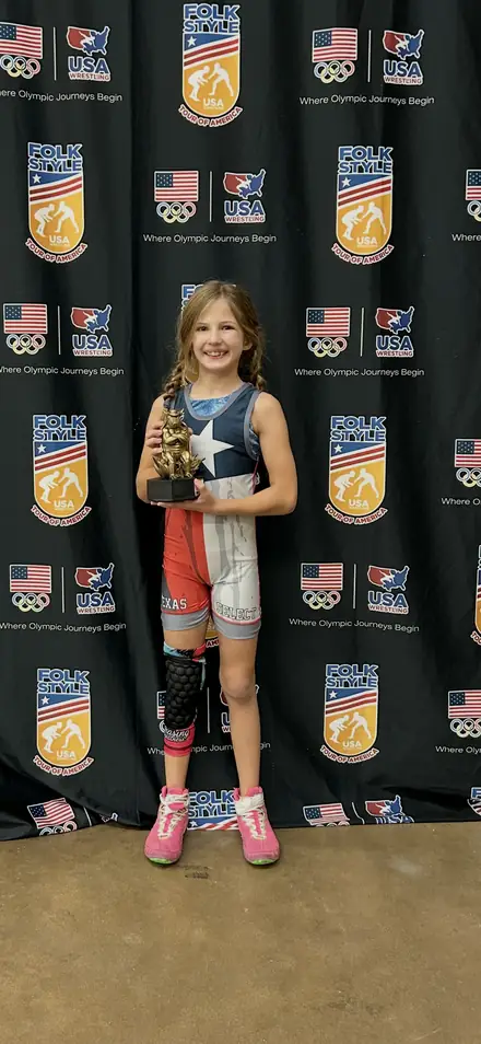An AWC wrestler with a medal at the Texas USA Wrestling awards backdrop
