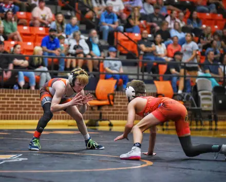 Two wrestlers face off in their stances during a match in the gym
