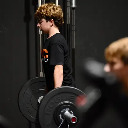 An AWC athlete loading plates at the squat rack.