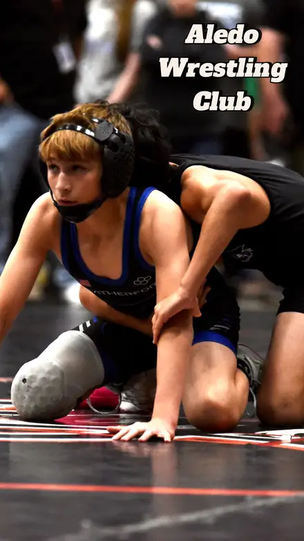 An AWC wrestler set in her stance on the mat, framed with the club name