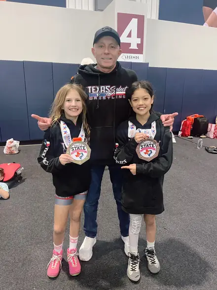 A coach with two AWC medalists after a tournament