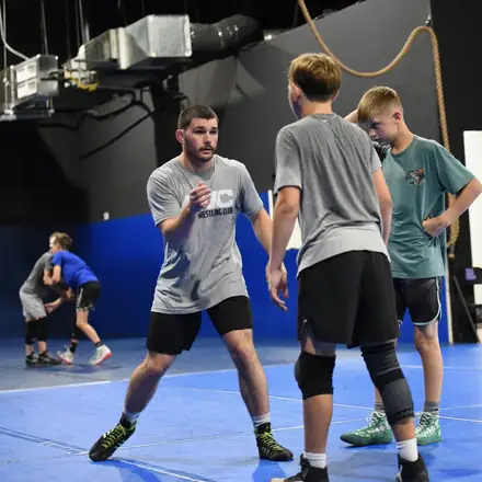AWC wrestlers working takedowns in a wide practice session.