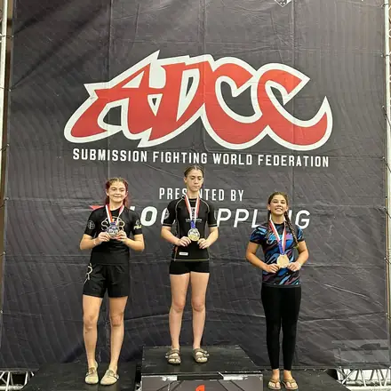 Three AWC athletes standing on the podium at an ADCC event.