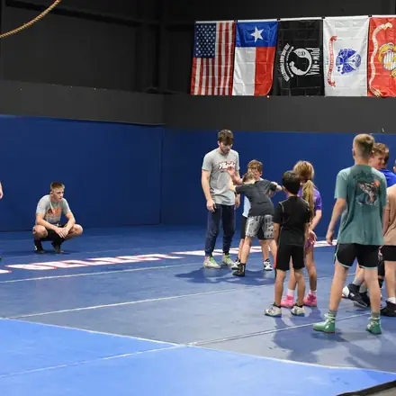 A mixed group of AWC athletes drilling takedowns during an evening practice.