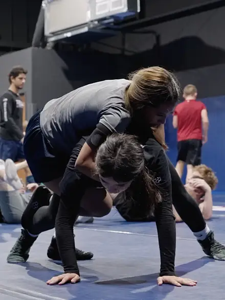 Two wrestlers drilling from the referee's position on the mat.