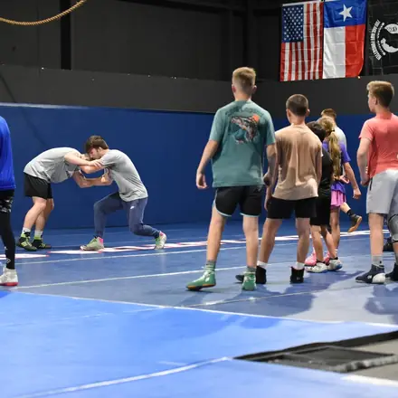 A wide view of the AWC room mid-practice with pairs drilling on the mat.
