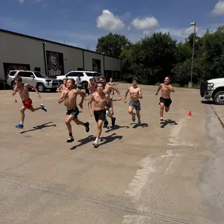 A pack of AWC athletes running sprints outside the gym.