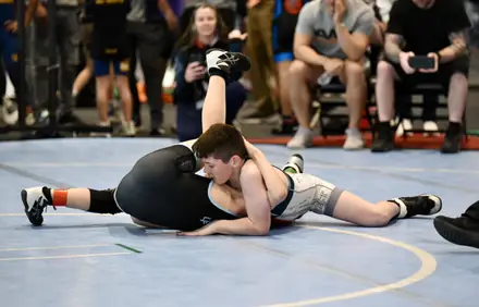 A wrestler works from the top position during a tournament match