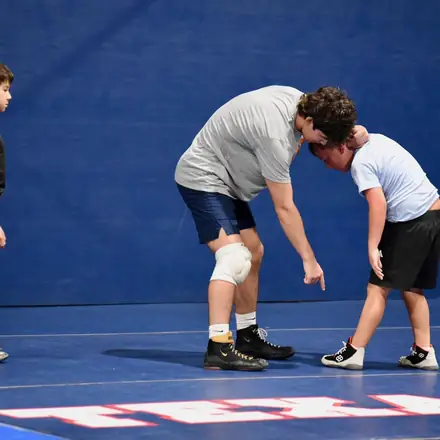 Two AWC wrestlers locked in a tie-up in the middle of the blue mat.