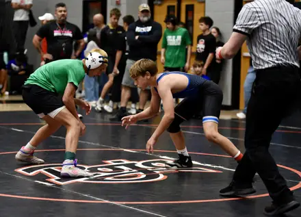 Two young wrestlers face off in a neutral stance during a match