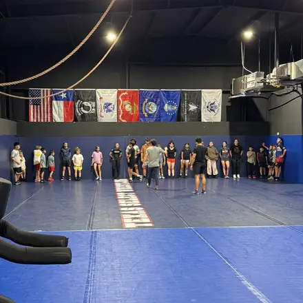 A wide view of a packed tournament floor with wrestlers warming up.