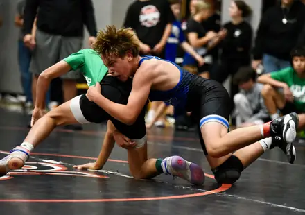 A wrestler finishes a takedown, driving through his opponent's hips