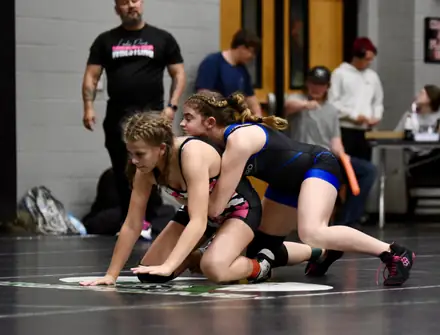 Two girls compete from the down position during a tournament bout