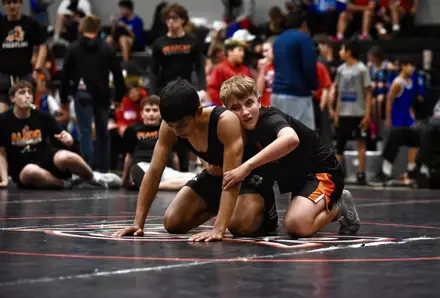 Two AWC wrestlers in club singlets set up on the mat during a bout
