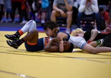 Two young wrestlers battle on the yellow competition mat
