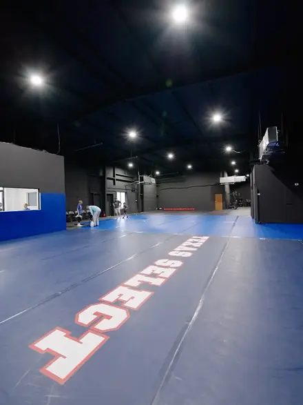 The empty mat room at the club, TX SELECT painted across the blue competition mat.