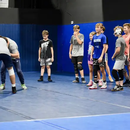 Youth wrestlers working through a drill on the blue mat.
