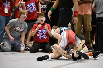 AWC teammates watch a match from the edge of the mat at a tournament