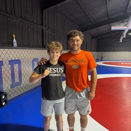 A coach and an AWC athlete on the tournament mat.