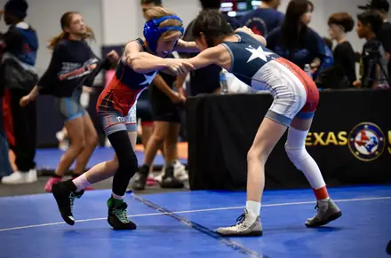 Two girls hand fight in a neutral stance at a Texas USA Wrestling event