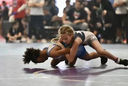 Two girls battle on the mat during a competitive bout
