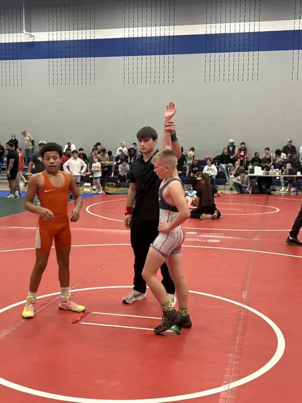 An official raises the winner's hand at the end of a tournament bout
