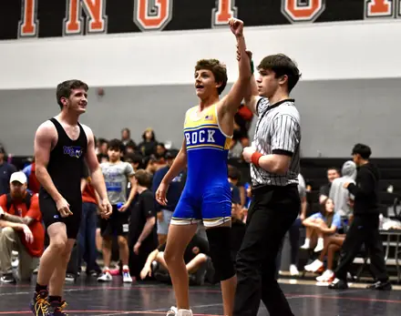 An official raises the winner's hand at the end of a tournament match