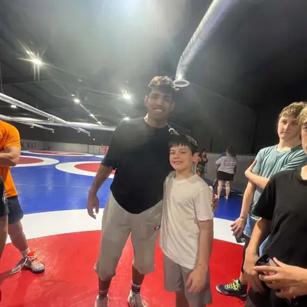 A coach with a group of young AWC wrestlers at the edge of the mat.