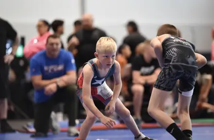 Two young wrestlers in their stances at the center of the mat