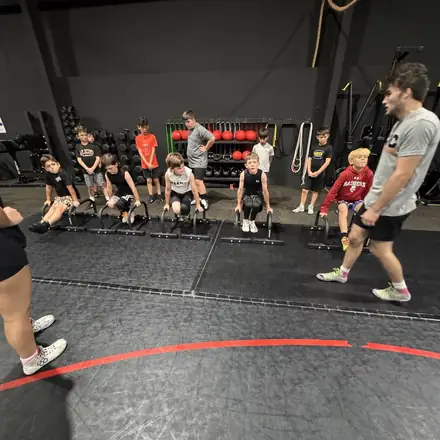 AWC athletes pushing weighted sleds across the turf.